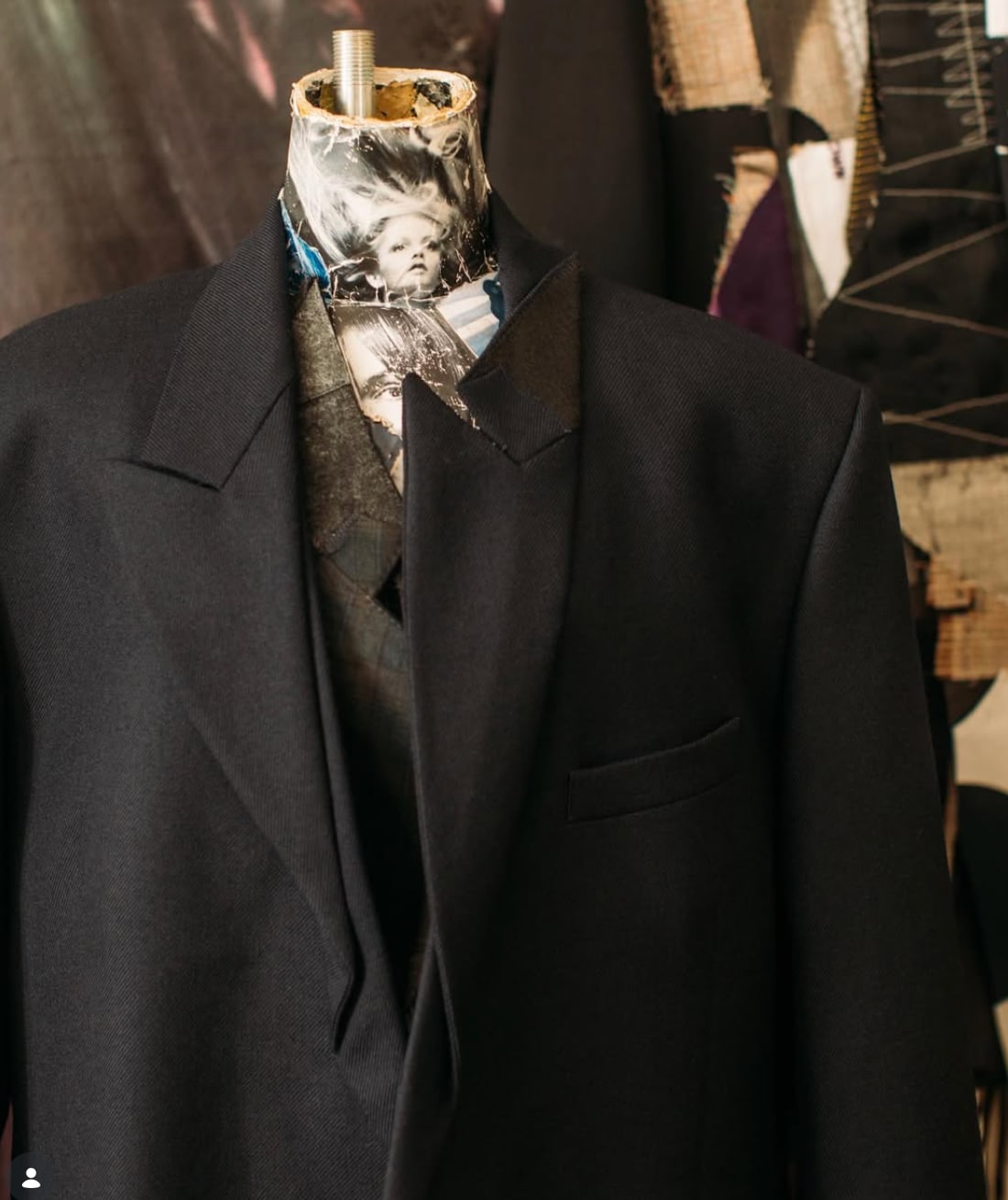 A black tailored jacket on a dress form, a printed scarf tucked in at the neck.