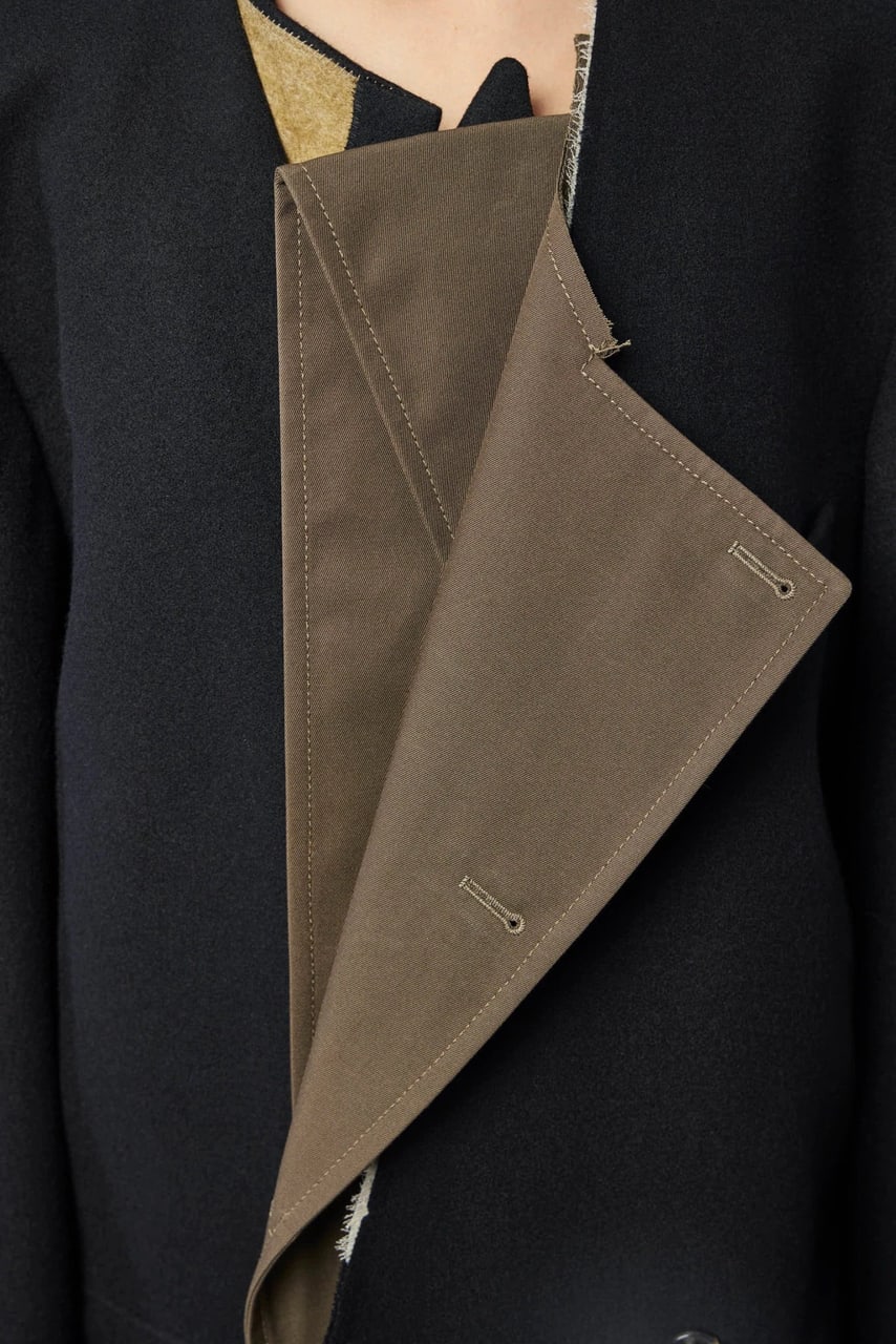 The olive facing laid back over the black front, its buttonhole at the point.
