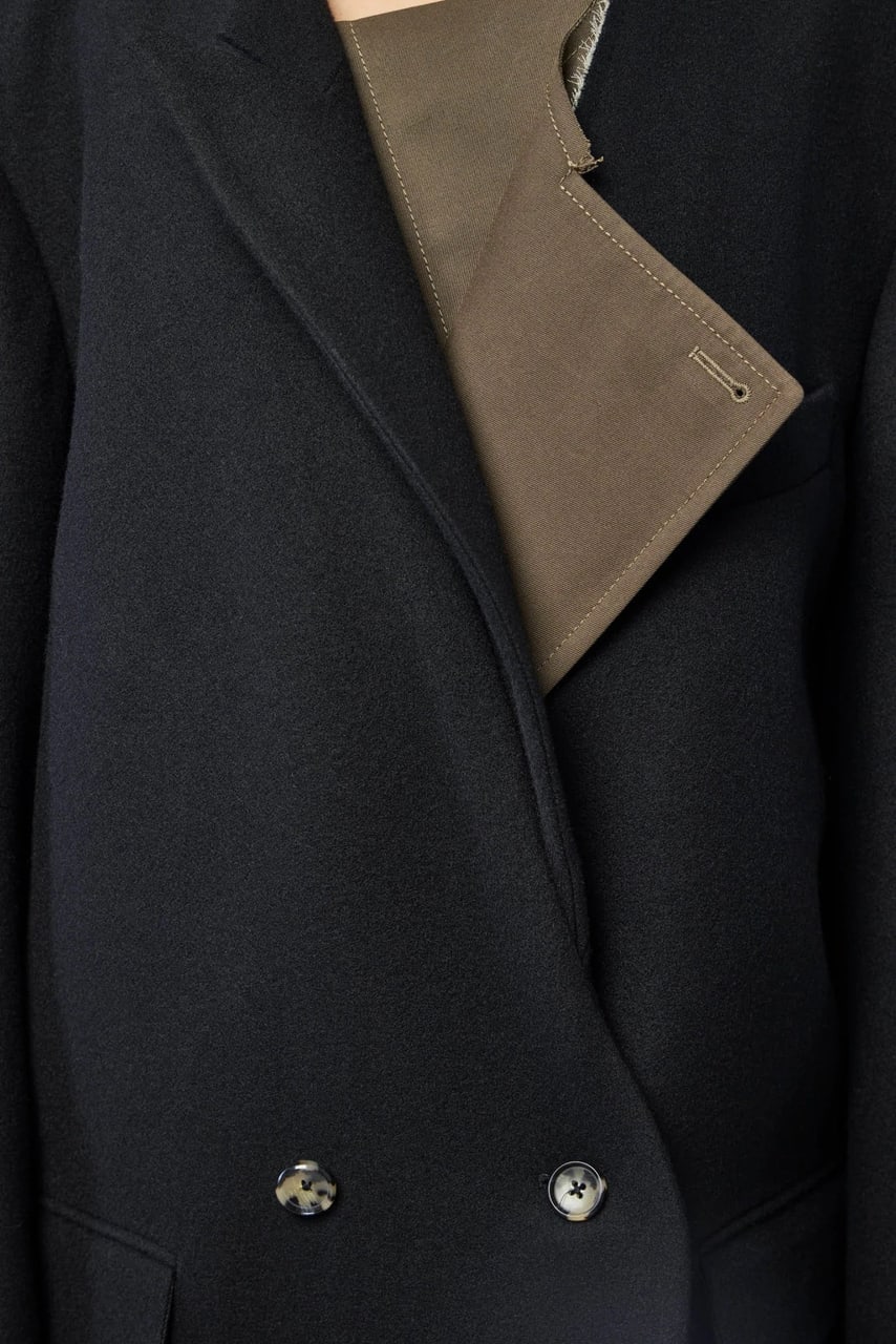 The front of the Parker Bis Coat: black wool, an olive lapel folded across it, two buttons at the waist.