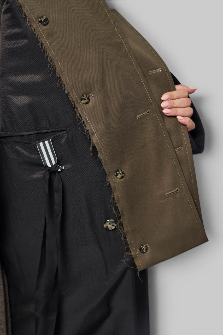 The coat held open on its olive inner front, a column of buttons and a black lining.