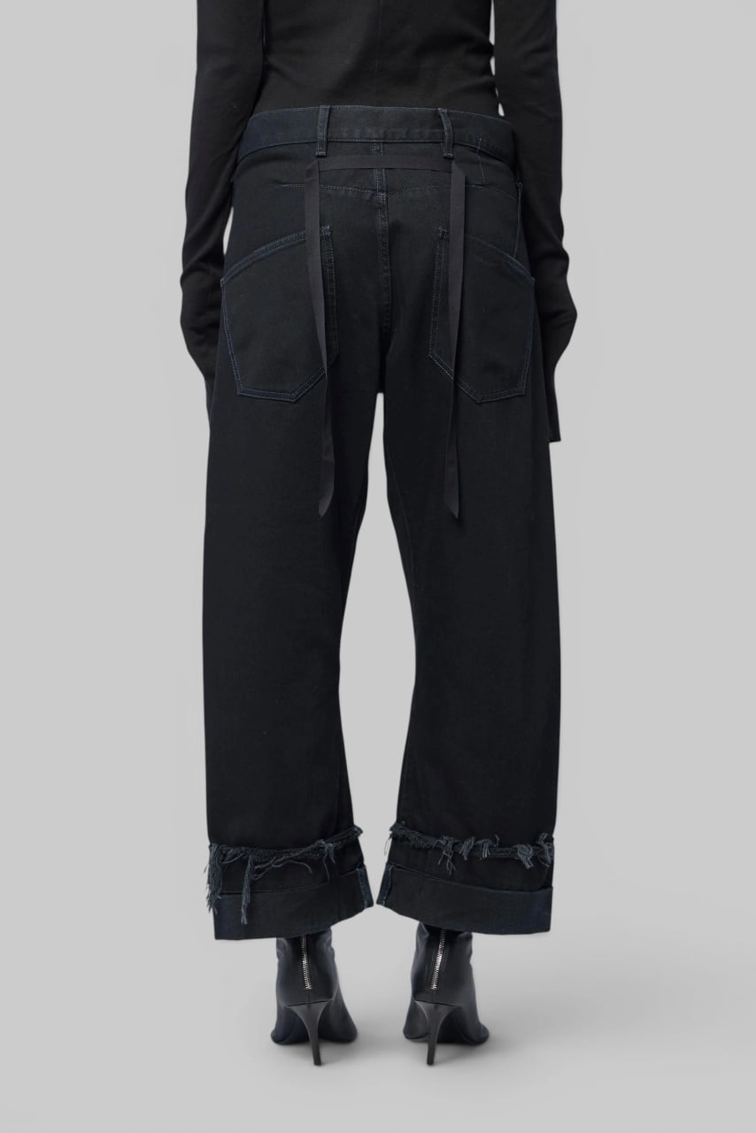 The jeans from behind, long straps hanging from the waistband.