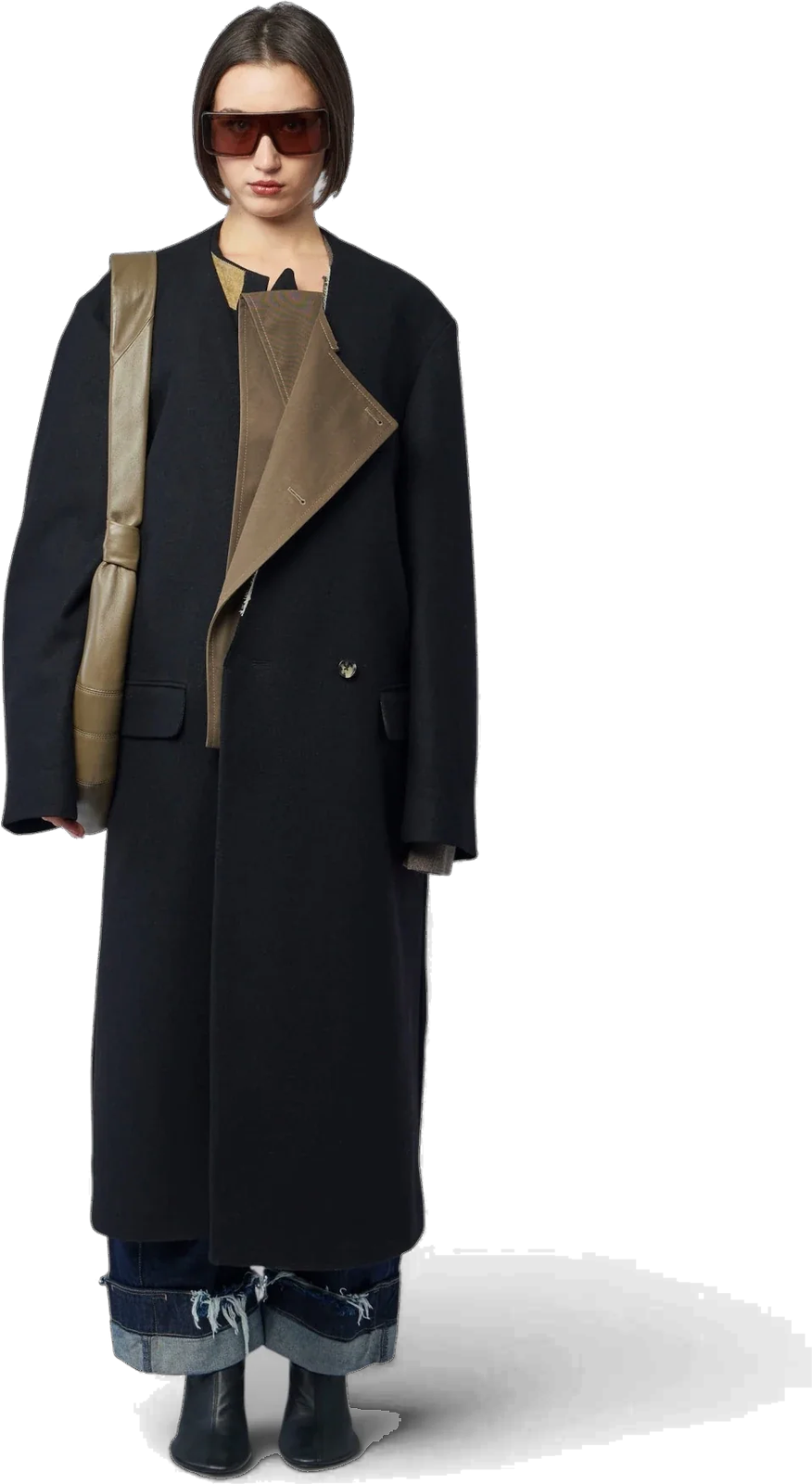 The Parker Bis Coat worn long and collarless: black wool, an olive lapel folded across the front, over jeans with deep turn-ups.